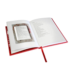 An open hardcover book with a red cover and ribbon bookmark, showing printed text pages and a small inset page or card inside the spread, isolated on a white background.